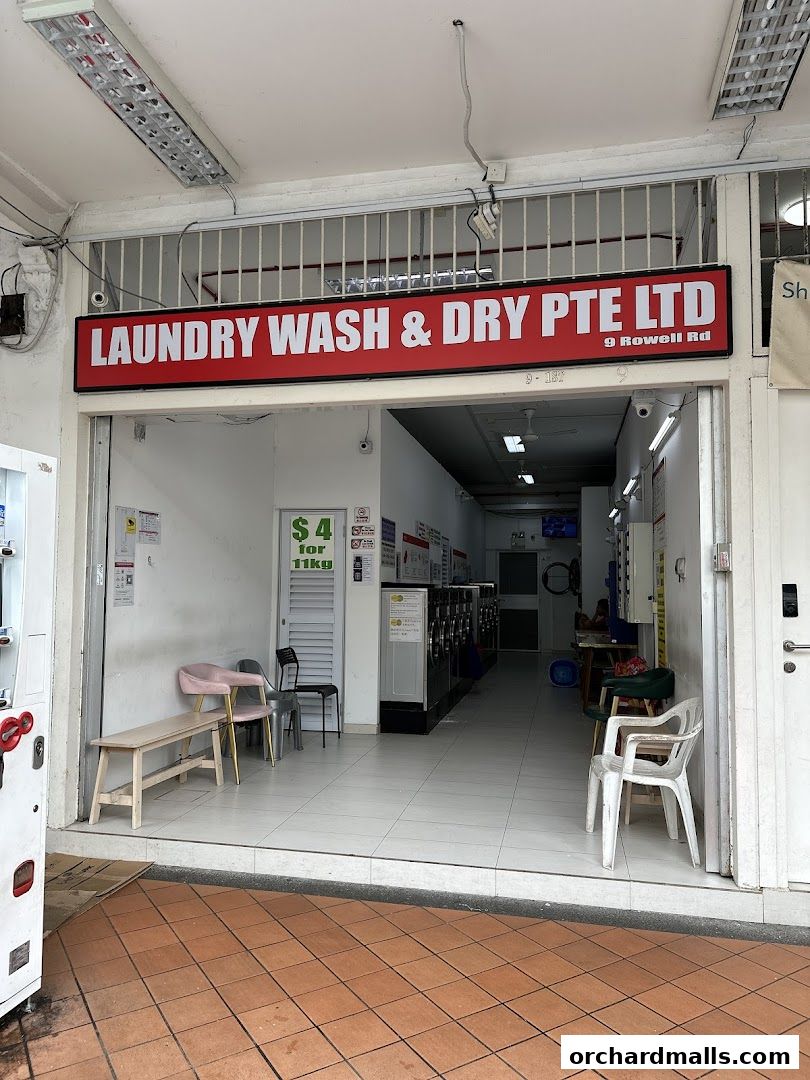 Exterior view of a laundromat with washing machines visible inside.
