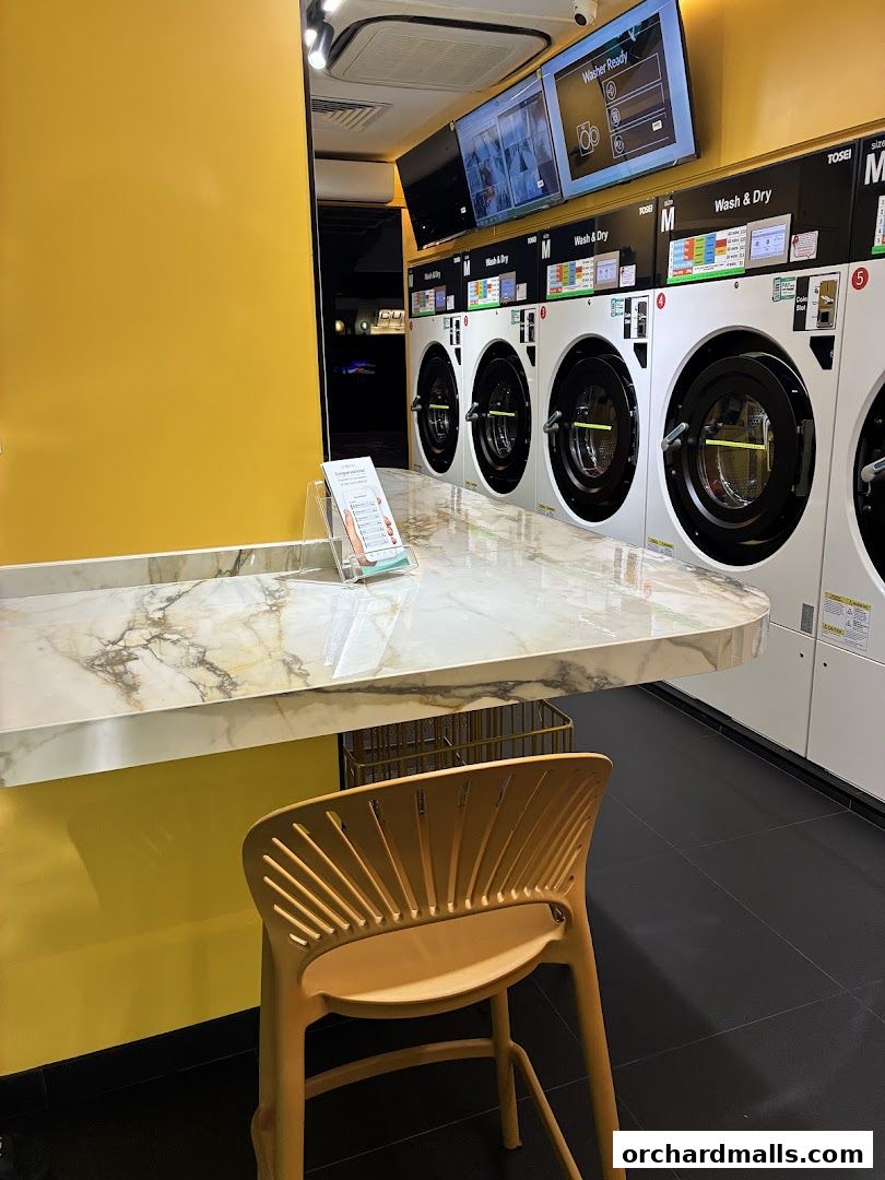 Interior of a modern laundromat with rows of washing machines and a marble counter.