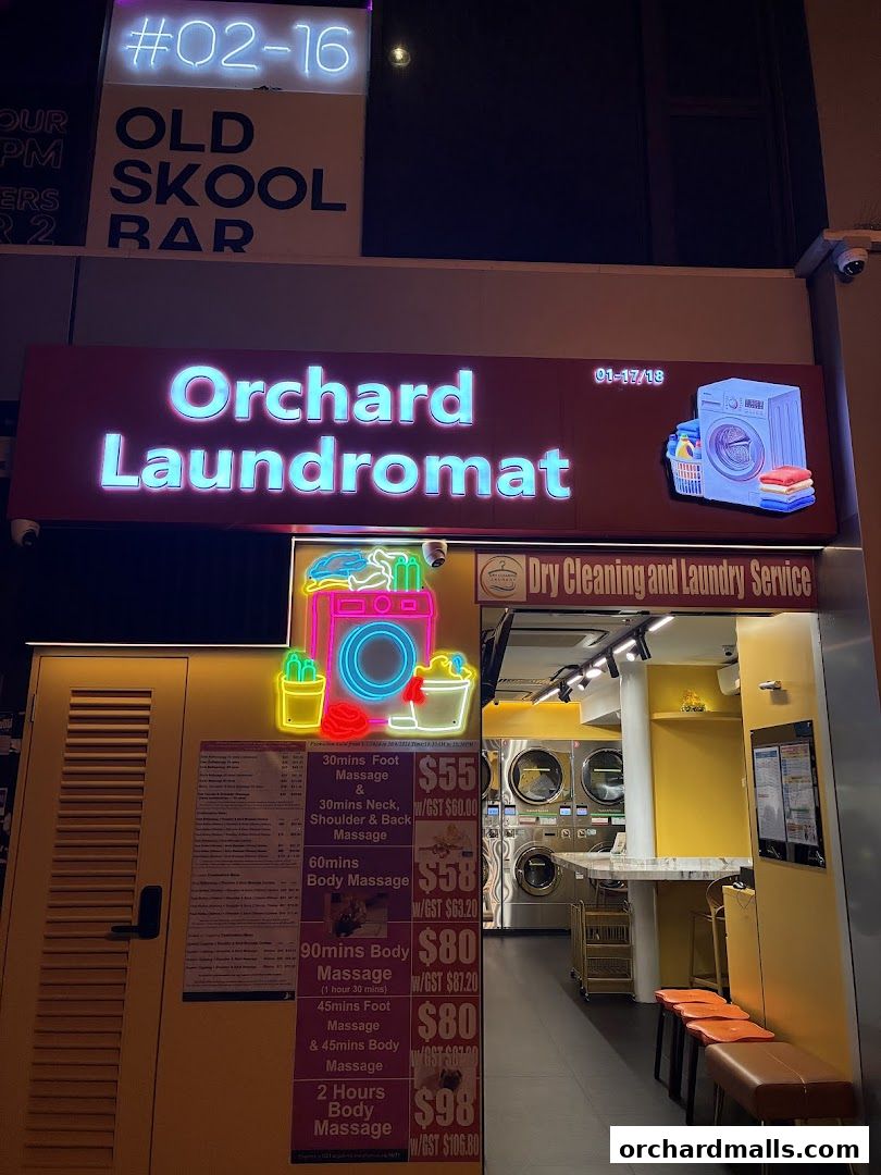 Exterior of Orchard Laundromat with neon signs and a price list for massages.