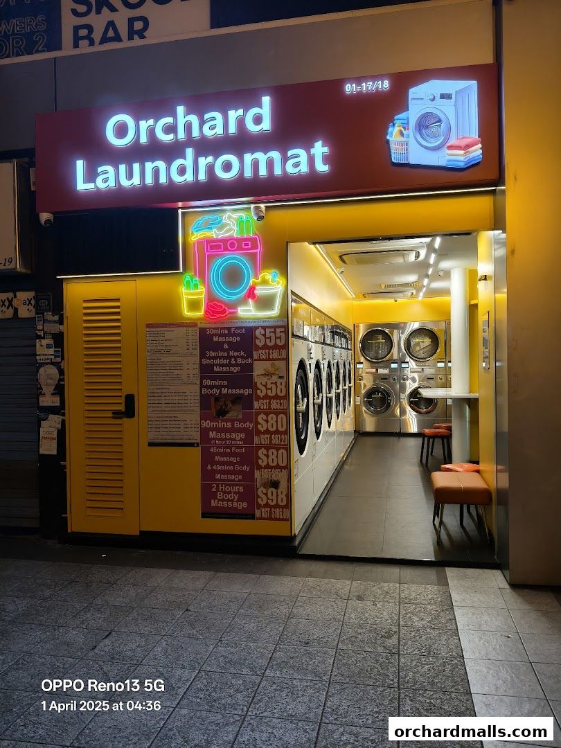 Exterior of Orchard Laundromat with neon signs and washing machines visible inside.