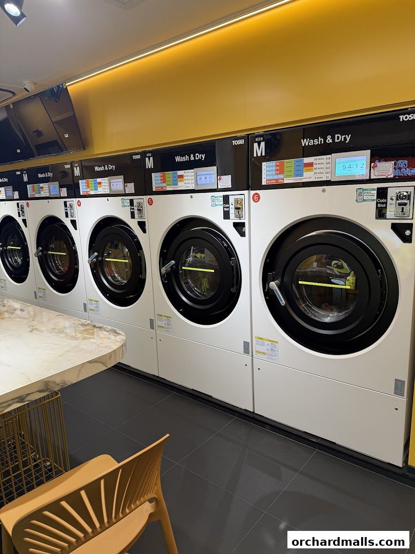 Row of modern washing and drying machines with digital displays and price information.