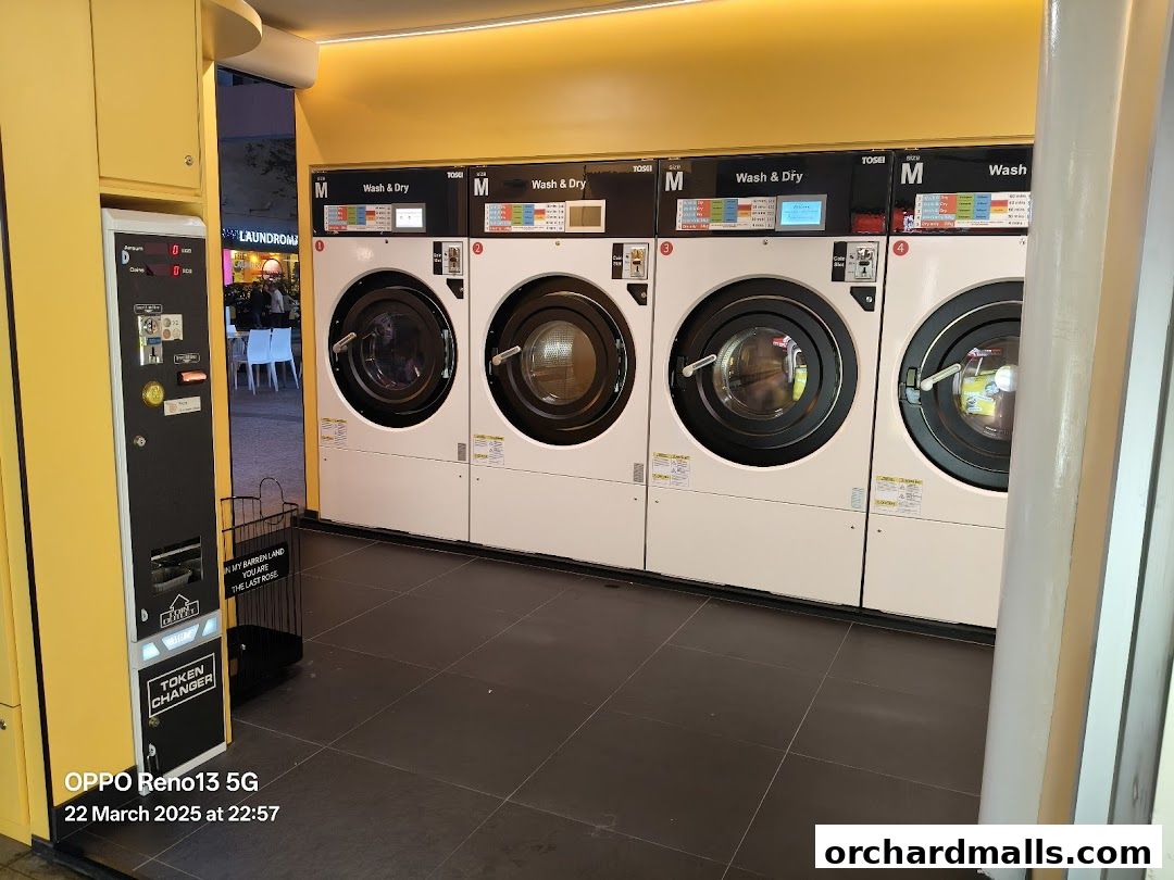 Modern laundromat with multiple wash and dry machines and a token changer.