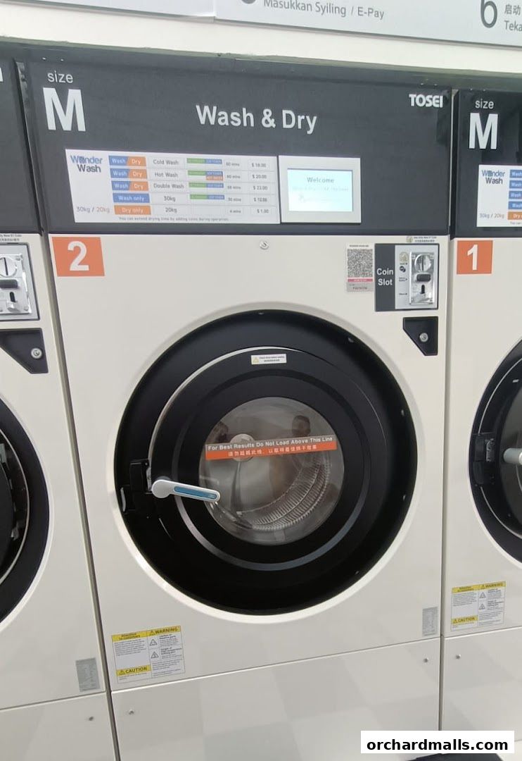 Close-up of a commercial washing machine with wash and dry options and pricing.