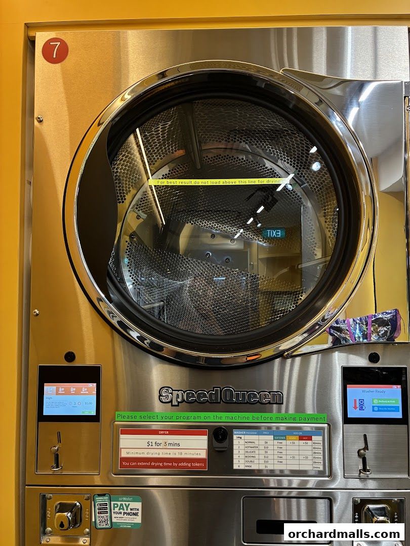 A close-up of a Speed Queen commercial dryer with payment and program selection interfaces.
