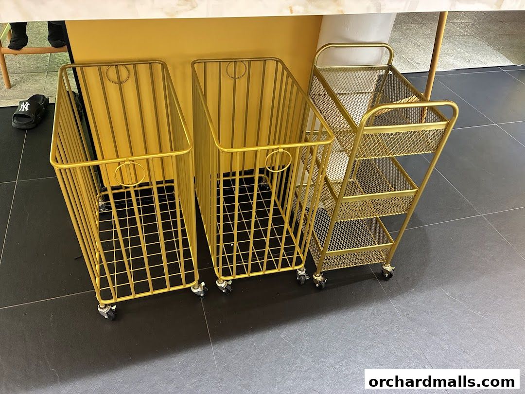 Three gold wire carts, two tall and one tiered, are on a dark tiled floor.