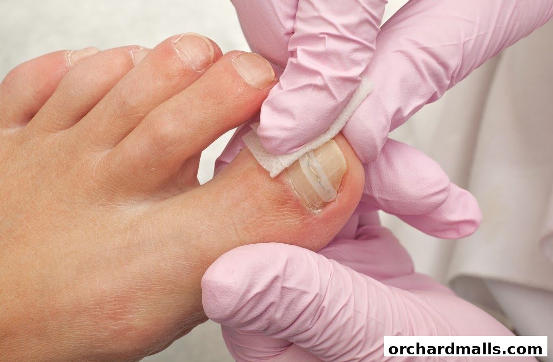 Close-up of a foot receiving nail treatment with pink gloved hands.