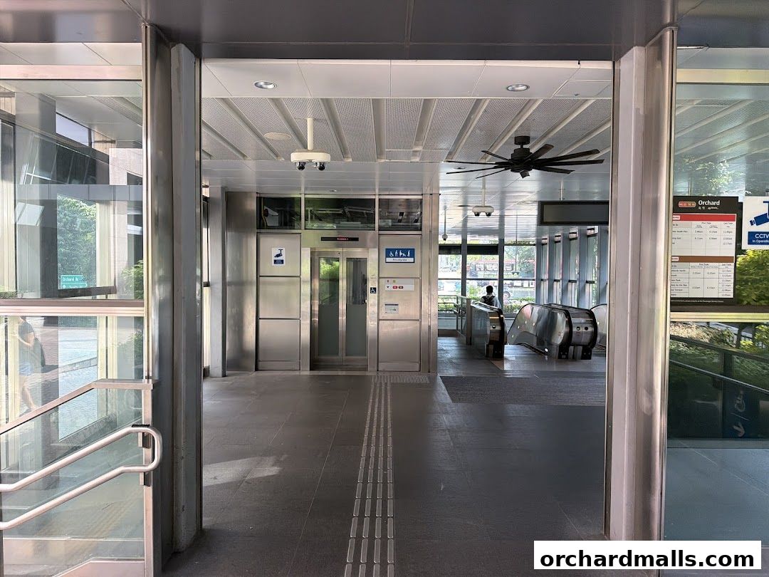 Entrance to a modern station with escalators, elevators, and signage.