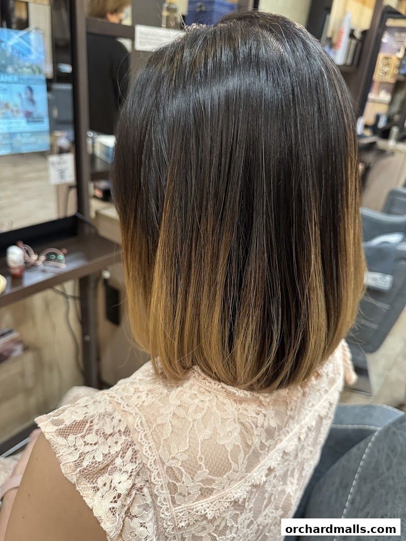 A person with a bob haircut with ombre coloring sits in a salon chair.