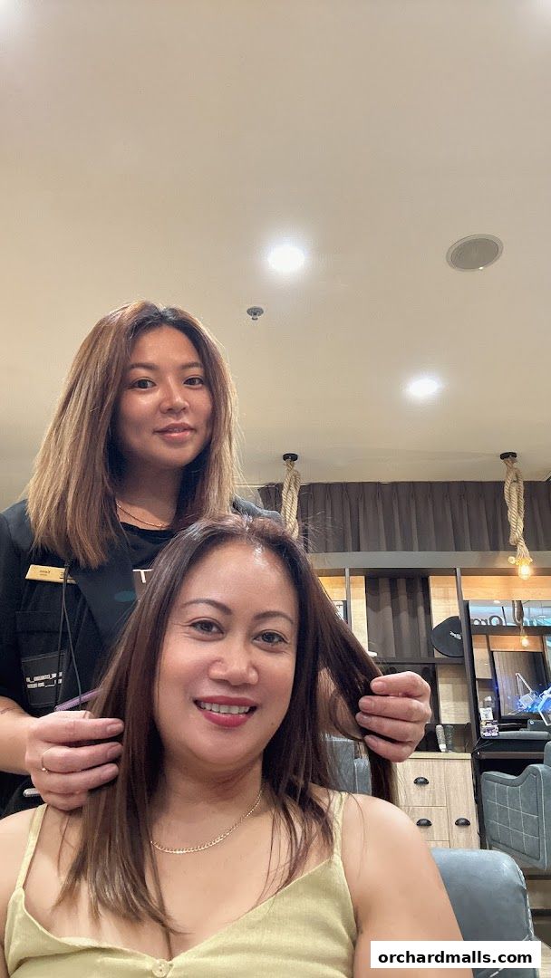 A stylist styles a client's hair in a salon setting.