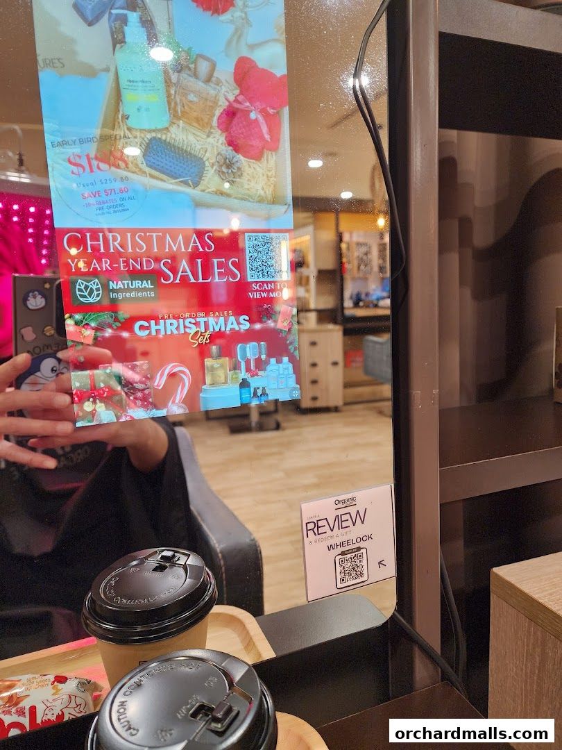 A reflection in a mirror shows a digital display advertising Christmas sales and hair products.