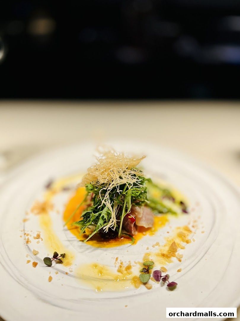 A beautifully plated dish with fresh greens, thinly sliced fish, and a vibrant sauce.