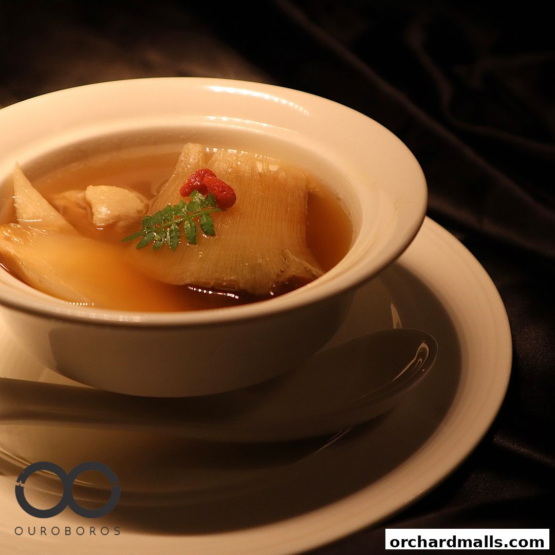 A close-up of a bowl of shark fin soup with a garnish of goji berries and parsley.