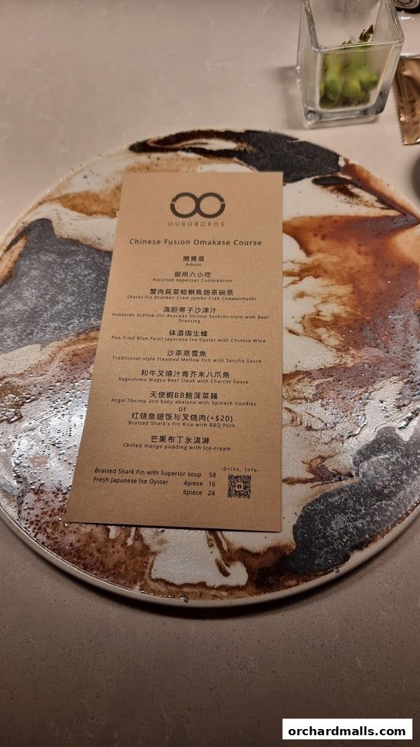 A menu for OUROBOROS Chinese Fusion Omakase Course is laid out on a decorative plate.