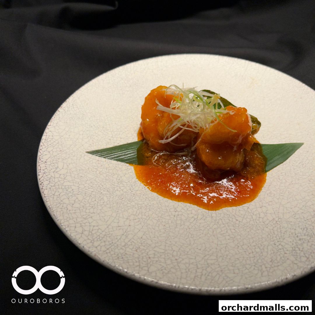 A plate of delicious Chinese-style shrimp with a vibrant orange sauce and garnish.