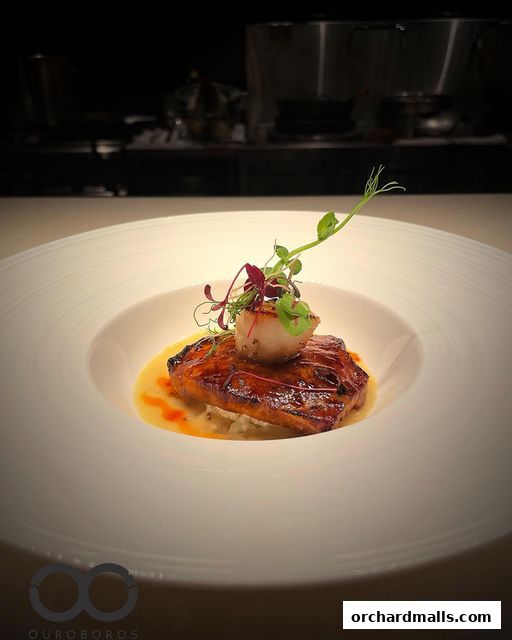 A beautifully plated dish of glazed fish with a scallop and microgreens.