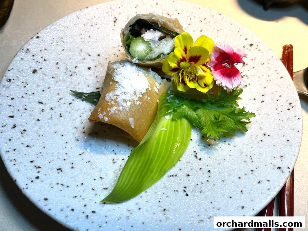 A beautifully plated spring roll with edible flowers and greens.