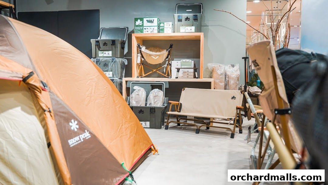 An indoor display of camping gear including tents, chairs, and storage boxes.