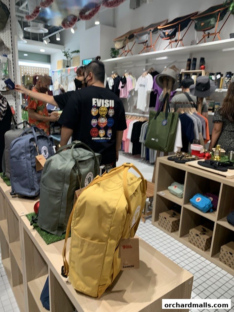 Inside an outdoor gear shop displaying backpacks, clothing, hats, and camping chairs.