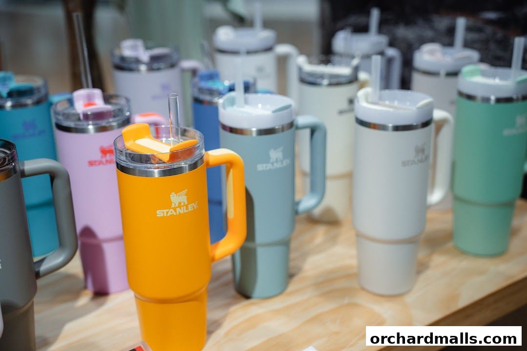 A collection of colorful Stanley tumblers with straws and handles displayed on a wooden surface.