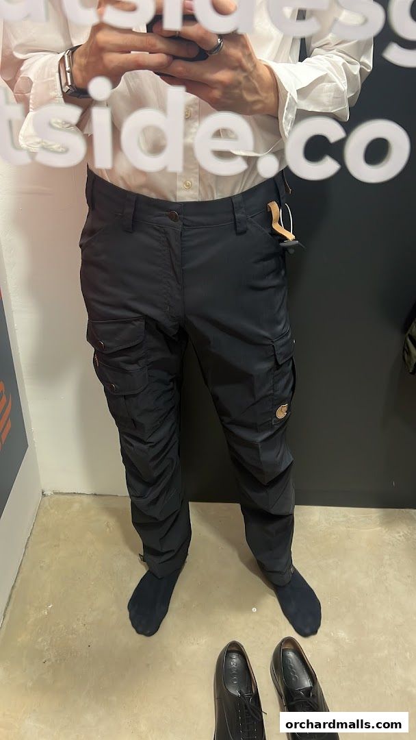 Person trying on black cargo pants in a retail store fitting room.