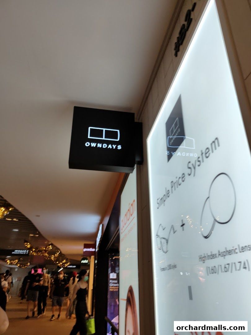 The OWNDAYS shop front with its illuminated sign and a display about their simple price system.