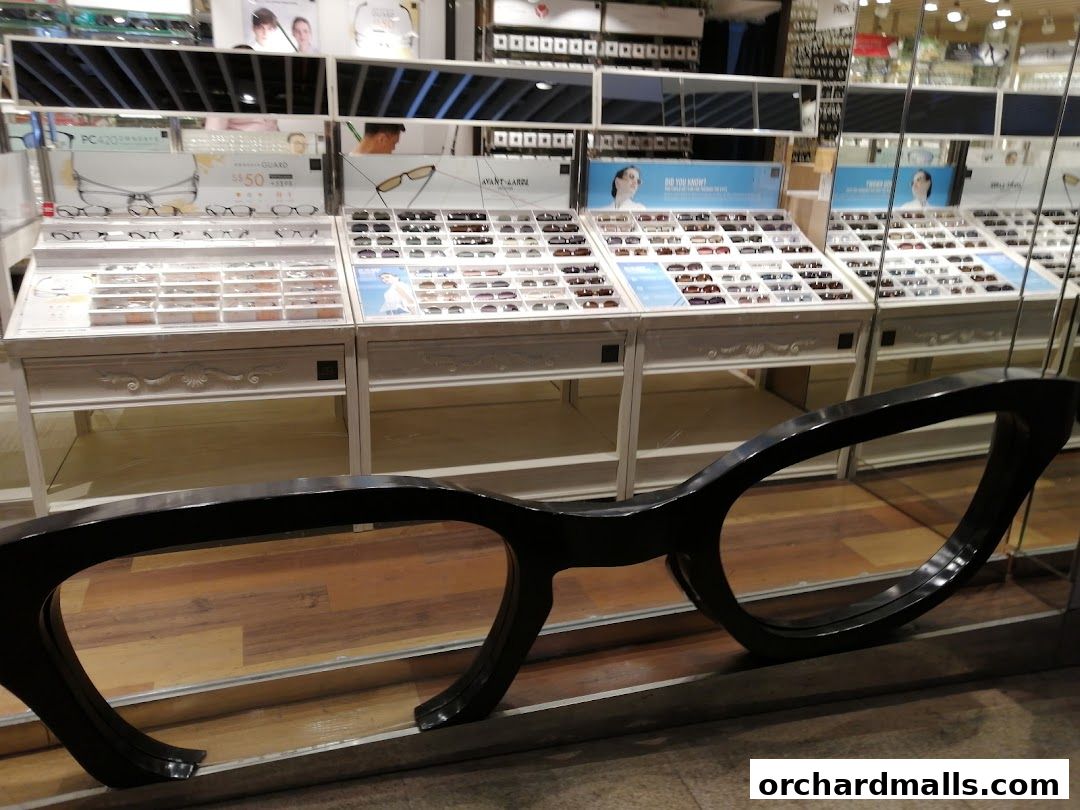 A display of eyeglasses and sunglasses inside a retail store with a large decorative pair of glasses in the foreground.