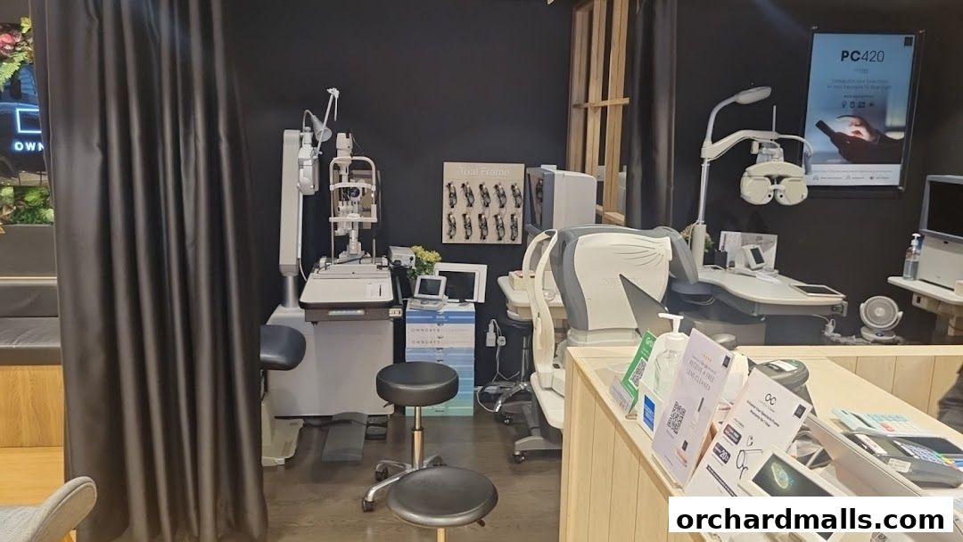 Interior view of an optical shop with eye examination equipment and a counter.