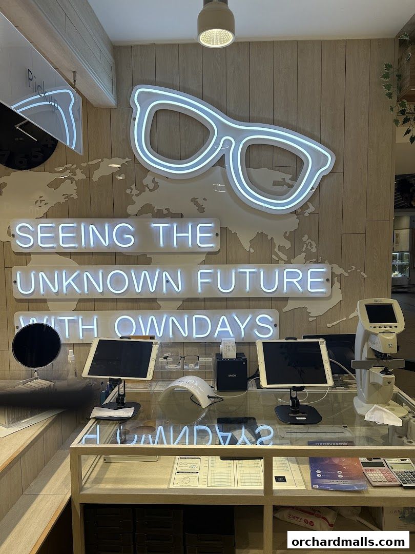 Interior shot of OWNDAYS ION Orchard with neon signs and optical equipment.