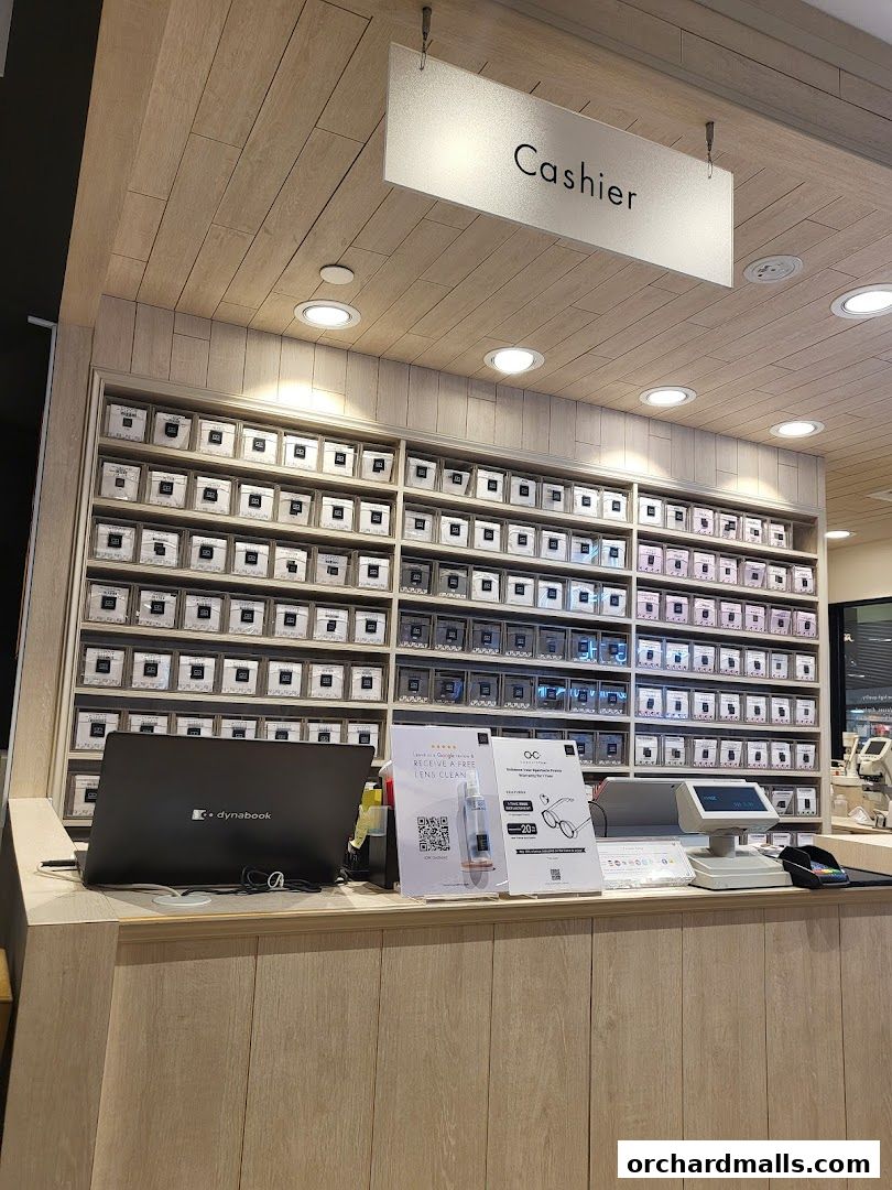 The cashier counter of an eyewear store with shelves of glasses and a laptop.