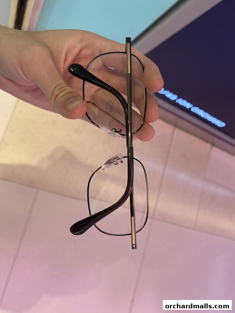 A hand holds a pair of stylish black-rimmed eyeglasses.