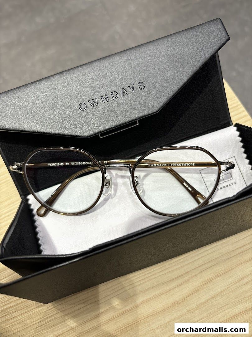 A pair of stylish eyeglasses in a black OWNDAYS case with a cleaning cloth.