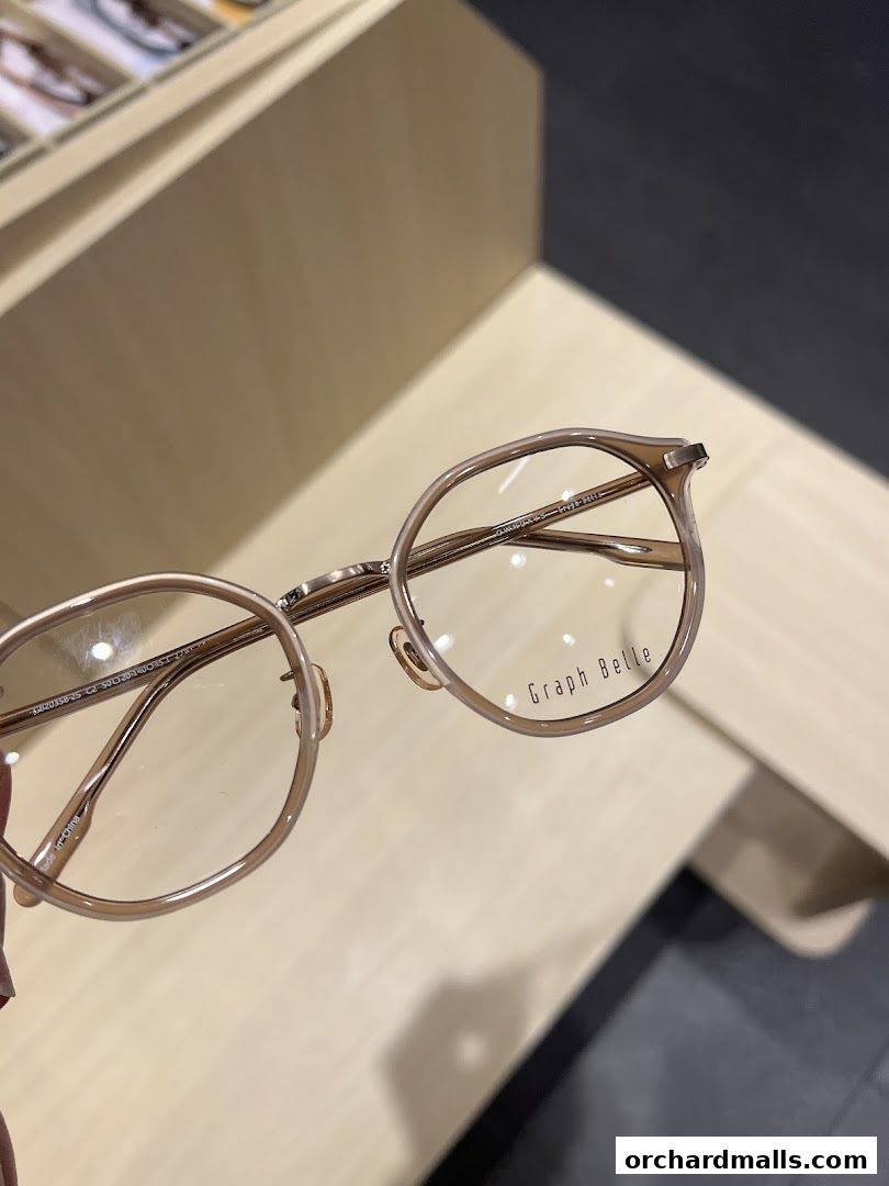Close-up of stylish, round, light brown eyeglasses with the brand name 'Graph Belle' visible.