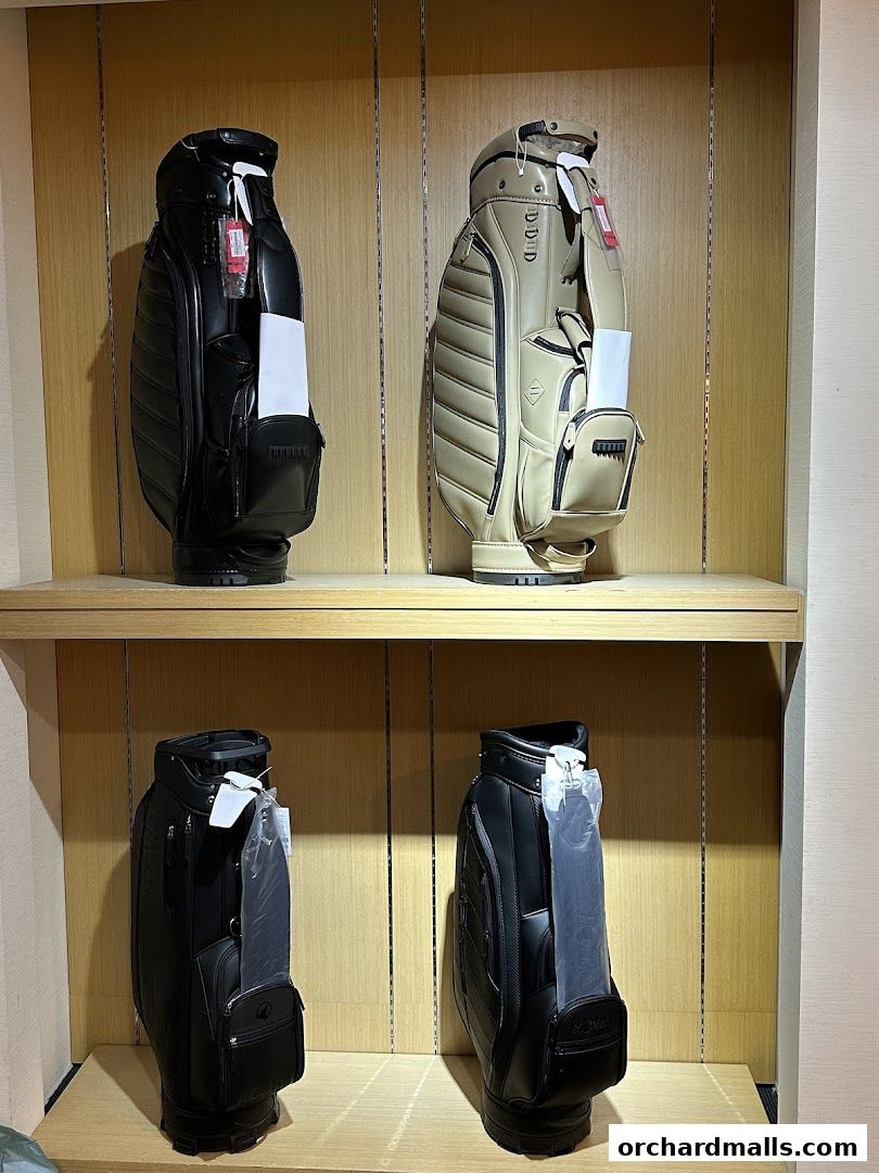 Four stylish golf bags displayed on shelves in a retail store.