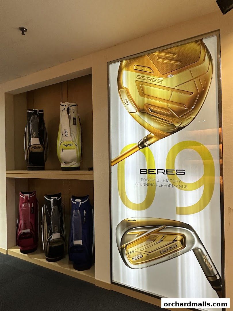 Golf bags displayed on shelves next to a large advertisement for Honma Beres golf clubs.
