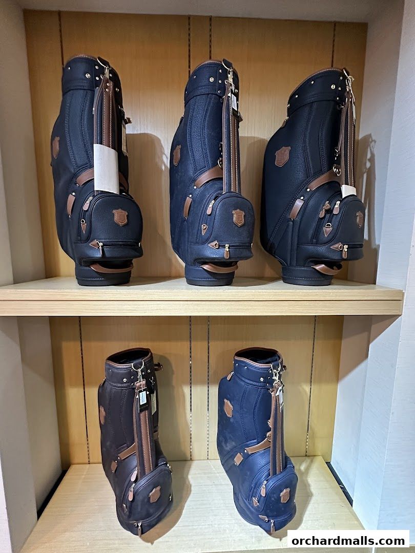 Five stylish golf bags are displayed on wooden shelves in a retail store.