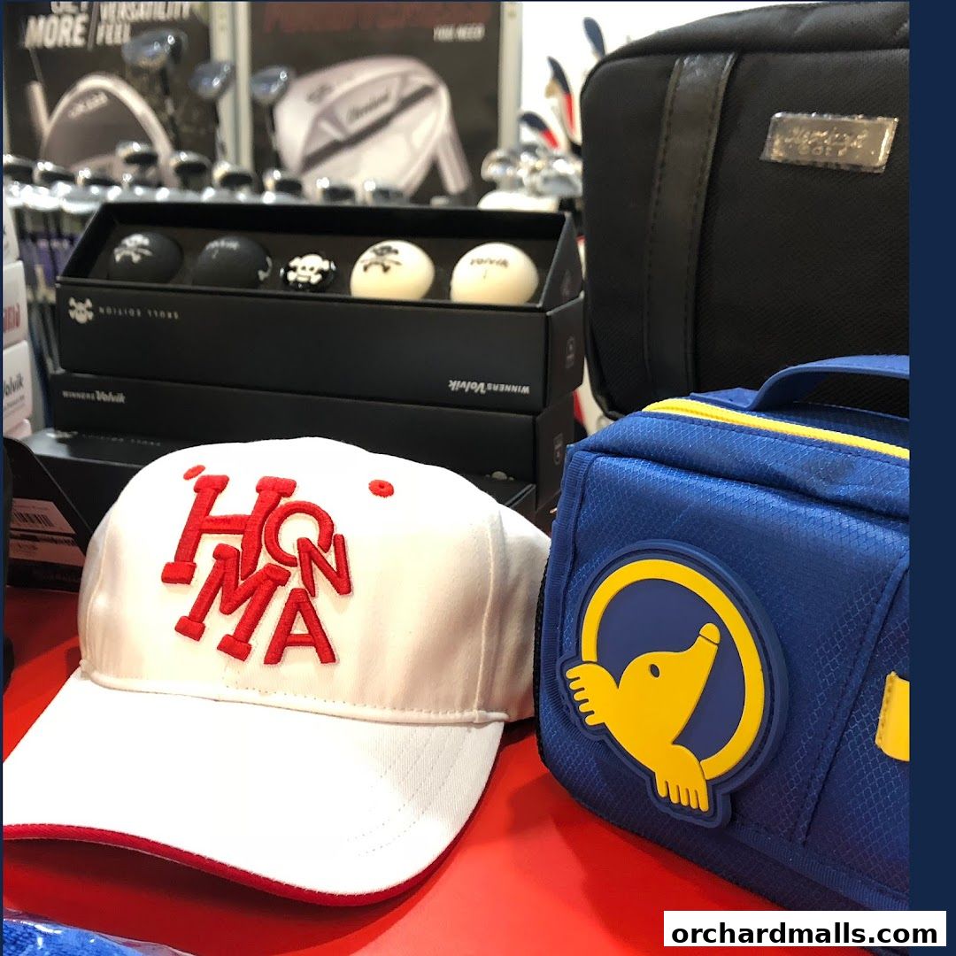 A white Honma golf cap and golf accessories are displayed on a red surface.