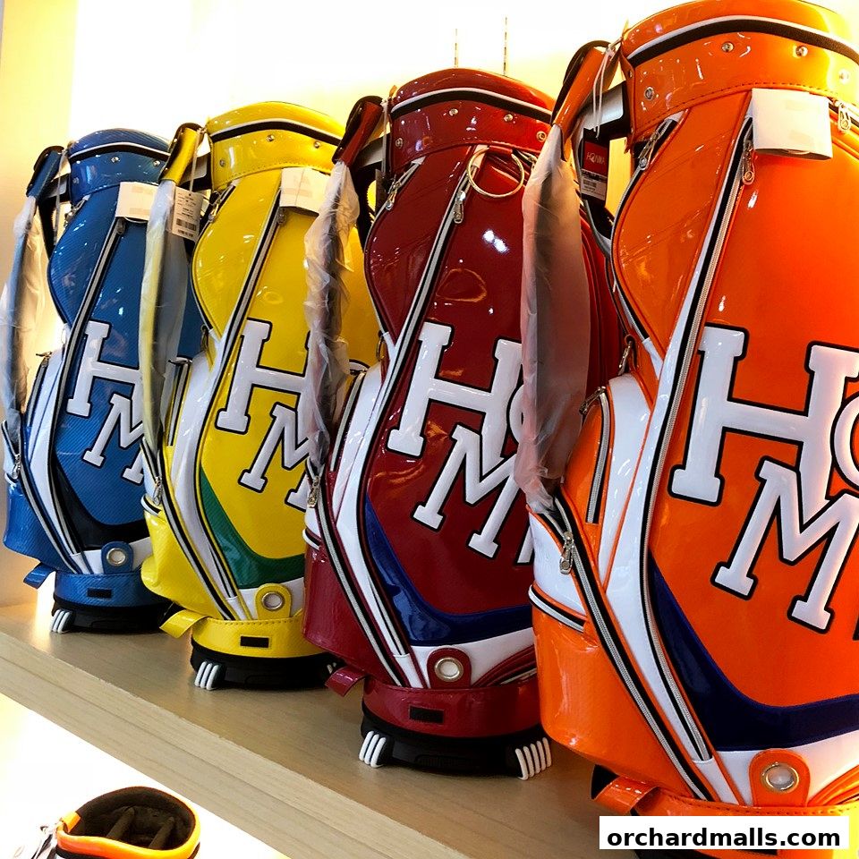 A row of colorful, glossy golf bags with the 'HM' logo displayed prominently.