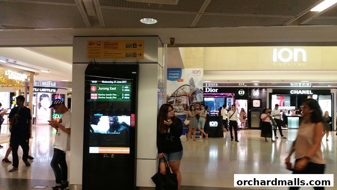 People walk through a mall with shops like Dior and Chanel, and an ION Orchard sign.