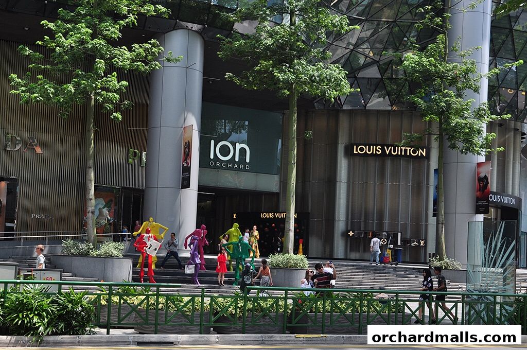 The ION Orchard shopping mall entrance with Louis Vuitton and Prada stores, and colorful statues.