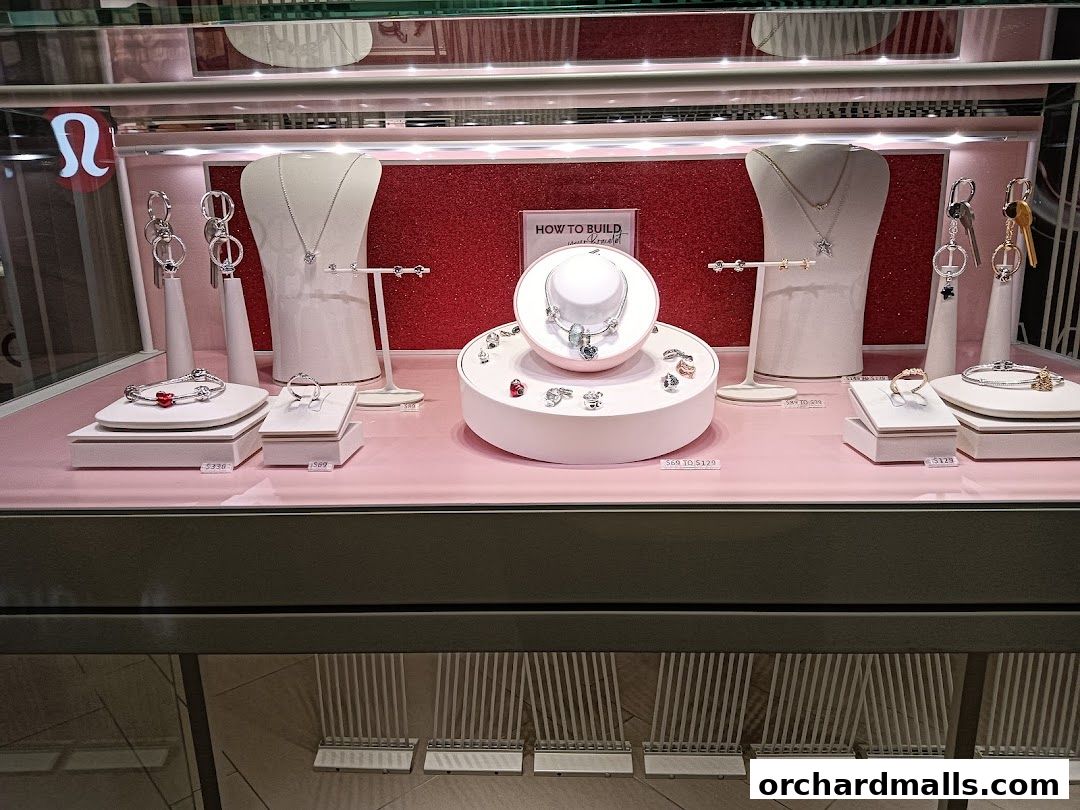 A display case showcasing Pandora jewelry, including necklaces, bracelets, rings, and charms.