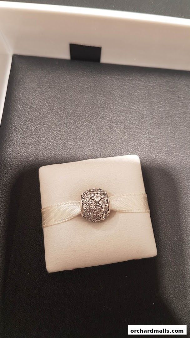 A close-up of a sparkling Pandora charm on a white display cushion.