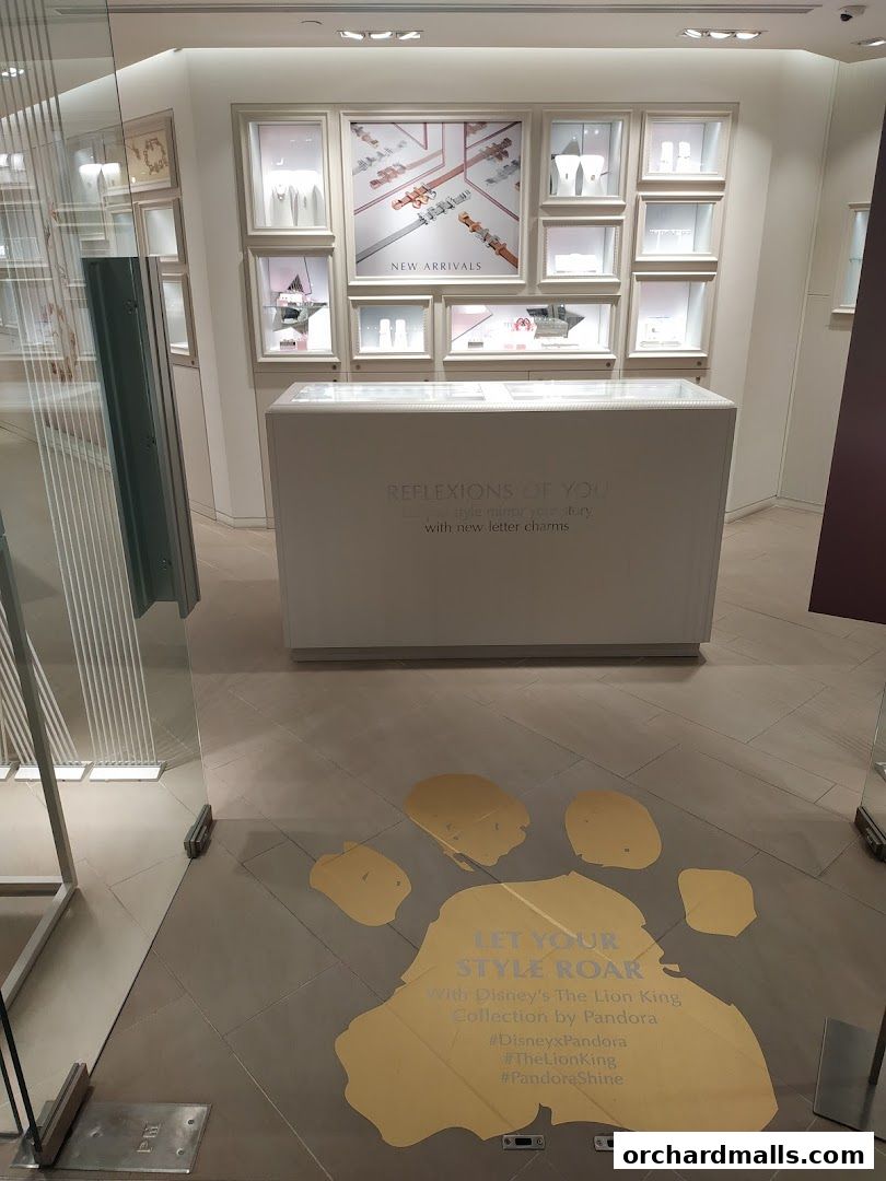 Interior view of a Pandora jewelry store featuring new arrivals and a Disney Lion King collection.