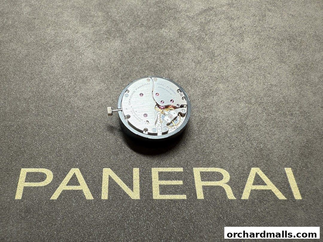 A close-up of a Panerai watch movement on a textured surface with the Panerai logo.