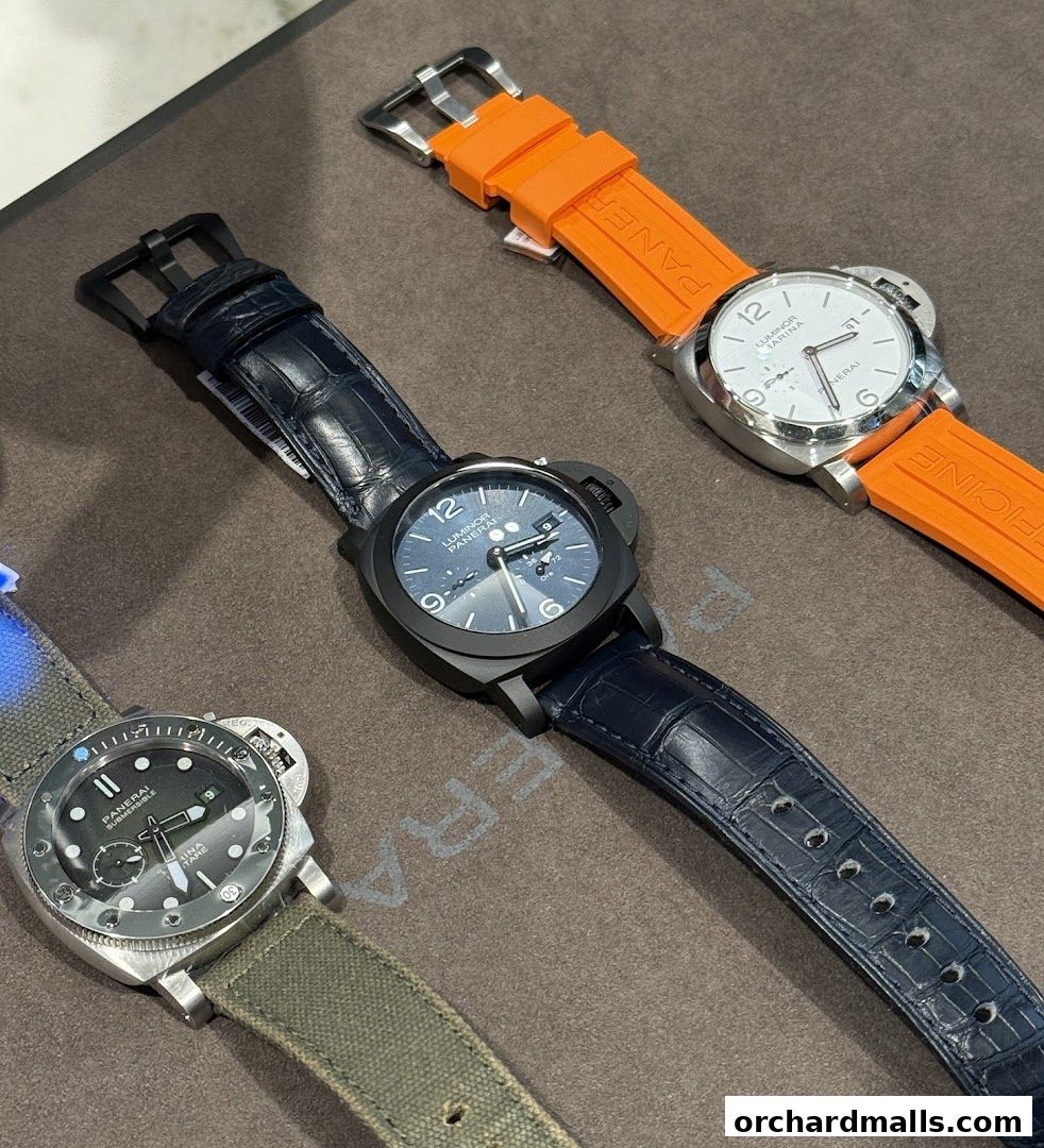 Three Panerai watches with different straps are displayed on a brown surface.