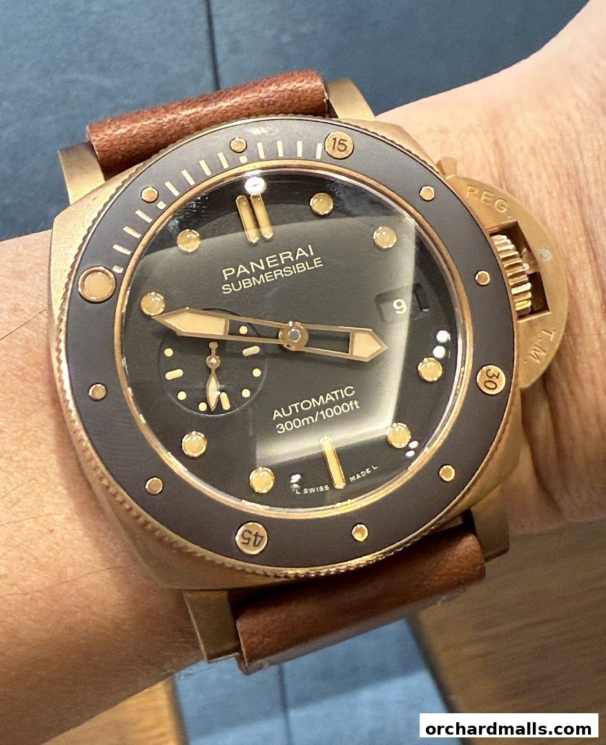 A close-up shot of a Panerai Submersible watch with a bronze case and brown leather strap.