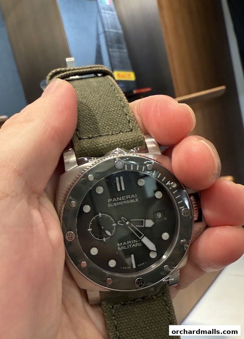 A close-up shot of a Panerai Submersible watch with a green canvas strap.