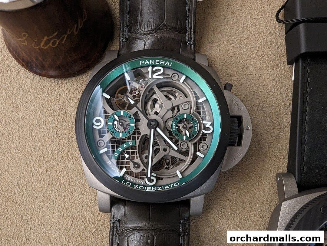 A close-up of a Panerai "Lo Scienziato" skeleton watch with a green bezel and alligator strap.