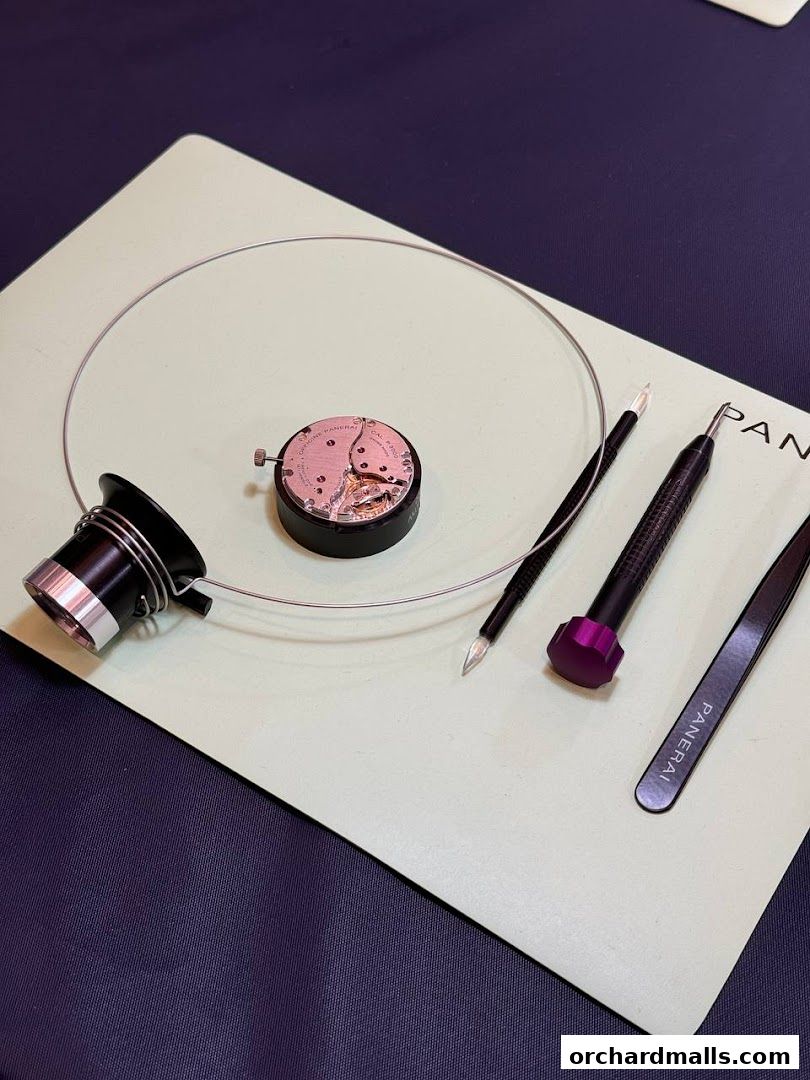 Watchmaking tools and a disassembled watch movement are laid out on a workbench.