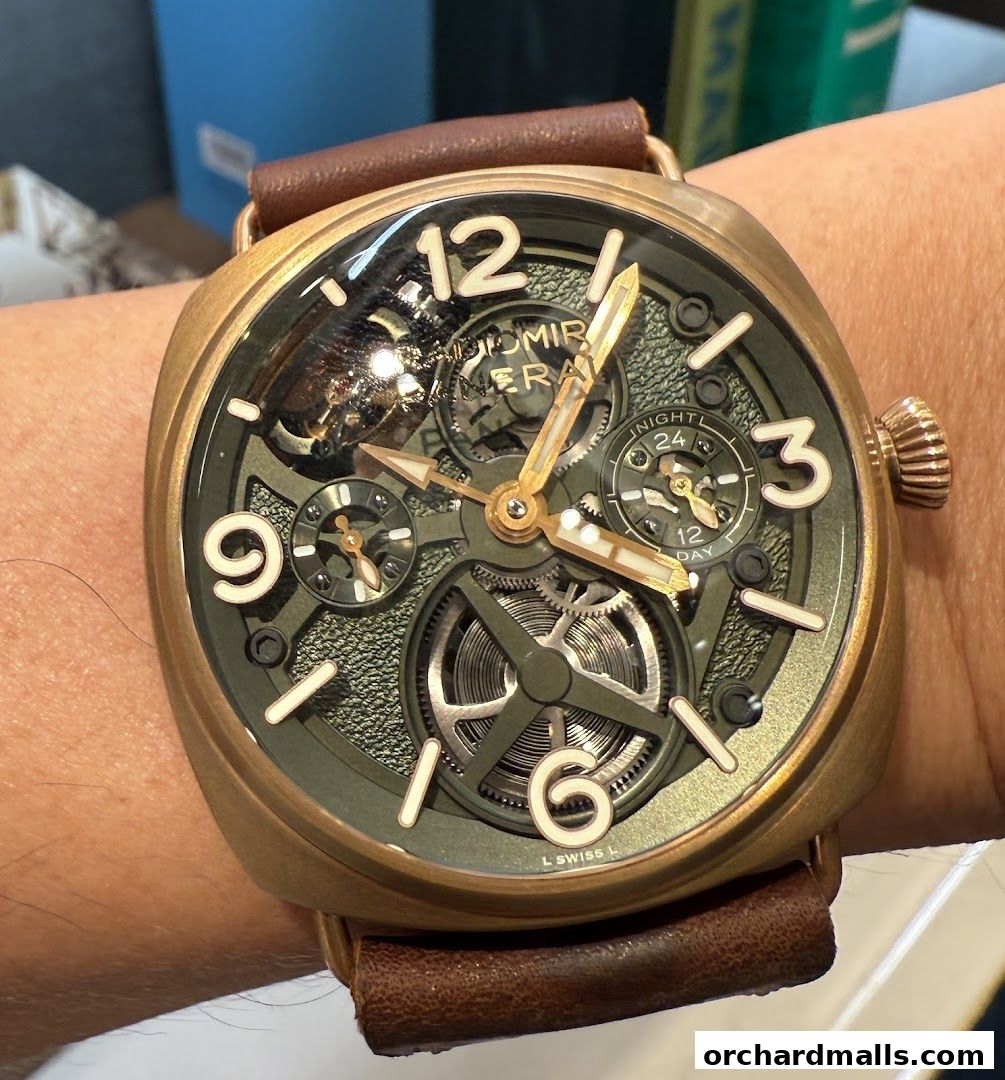 A close-up shot of a Panerai watch with a green dial and brown leather strap.