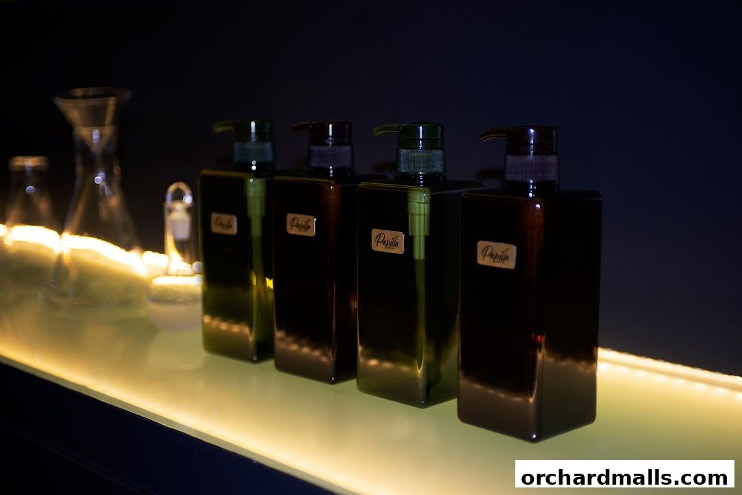 Four dark bottles with pump dispensers labeled 'Papilla' on a lit shelf.